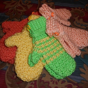 Puede incluir: Cuatro mitones de ganchillo en diferentes colores: naranja, amarillo, verde y rosa. Los mitones están hechos con un punto texturizado y tienen un diseño sencillo.