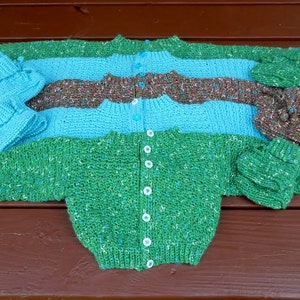 May include: Three knitted sweaters in green, blue, and brown with matching knitted hats. The sweaters are button-up and have a speckled texture.