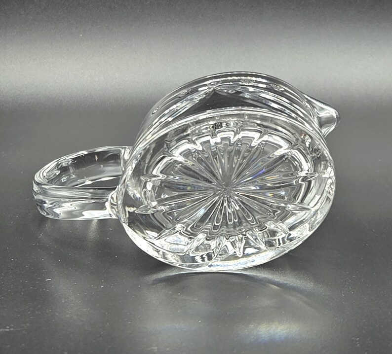 May include: A clear glass pitcher with a cut glass design. The pitcher has a round body and a handle.