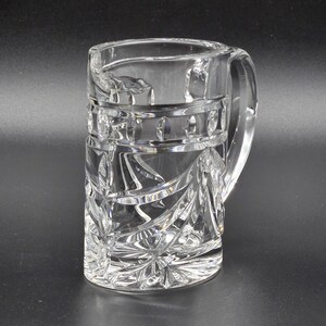 May include: A clear glass mug with a cut crystal design. The mug has a handle and is decorated with a geometric pattern.