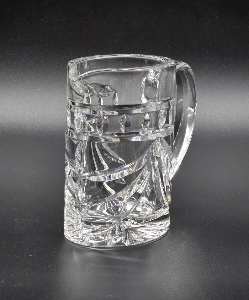May include: A clear glass mug with a cut crystal design. The mug has a handle and is decorated with a geometric pattern.