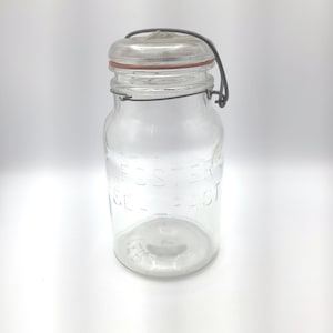 Pode incluir: Um frasco de vidro transparente com tampa de metal e fecho de arame. O frasco tem o texto em relevo "FOSTER SEAL FAST" na lateral. A tampa tem uma vedação de borracha vermelha. O frasco está vazio.