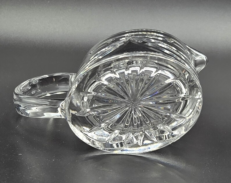 May include: A clear glass pitcher with a cut glass design. The pitcher has a handle and a spout.