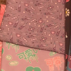 May include: A stack of three fabric squares with different patterns. The top square is purple with a repeating pattern of white syringes, bandages, and pills. The middle square is purple with a repeating pattern of green hearts, white pills, and white plus signs. The bottom square is pink with a repeating pattern of white hearts, bandages, and pills.