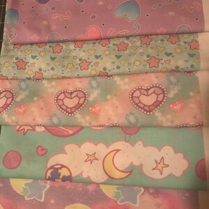 May include: Five different fabric swatches with pastel pink, blue, and green colors. The fabrics feature various patterns including hearts, stars, moons, and clouds.