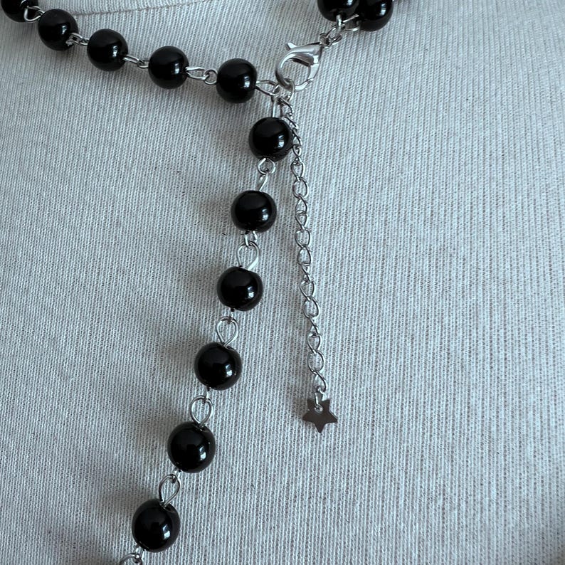 May include: A black beaded necklace with a silver chain and a star charm.