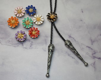 以下が含まれることがあります： さまざまな色の花型のボータイクラスプとボータイのコレクション。クラスプはピンク、青、オレンジ、緑、白、紫、赤など。ボータイは黒いコードとシルバー色のチップが付いています。