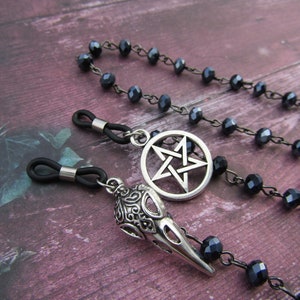May include: Black beaded eyeglass chain with a silver pentagram charm and a silver skull charm.