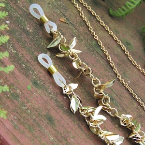May include: Gold chain with leaf-shaped charms and clear silicone ends. The chain is designed to hold glasses.