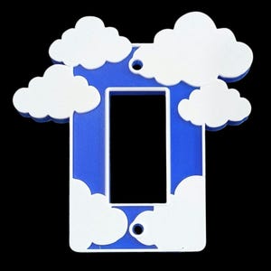 Könnte beinhalten: Ein blauer Lichtschalter-Abdeckung mit einem weißen Wolken-Design. Die Abdeckung hat eine rechteckige Öffnung für den Schalter.