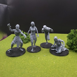 May include: Four grey miniature zombie figures in different poses. One figure has its arms raised, another is running, and a third is kneeling. Each figure is on a black circular base, against a green and black backdrop.