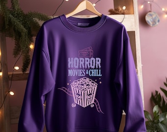 May include: Purple sweatshirt with a graphic design of a bucket of popcorn with skulls and the text "HORROR MOVIES & CHILL" with a ticket design above the text.