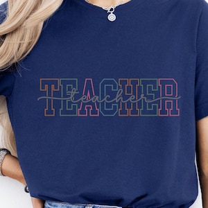May include: A navy blue t-shirt with the word "TEACHER" in colorful outlined letters. The word "teacher" is written in cursive underneath the letters.