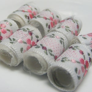 May include: Six white fabric hair ties with a pink and green floral pattern.