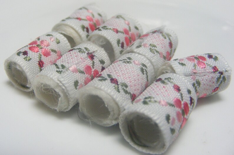 May include: Six white fabric hair ties with a pink and green floral pattern.