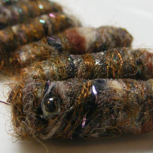 May include: A close-up of a set of brown and white fabric beads with gold and silver accents. The beads are made of a soft, fuzzy material and have a rustic, natural look.