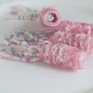 May include: Pink and white beaded fringe earrings with pink and white yarn tassels.