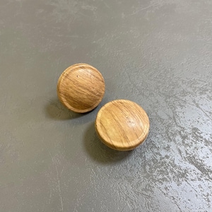 Peut inclure: Deux boutons ronds en bois avec un motif de grain de bois brun clair.