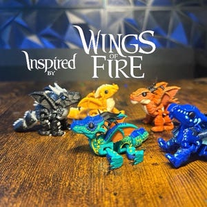 May include: Five small articulated dragon figurines inspired by Wings of Fire. The collection includes a black and white dragon, a yellow dragon, an orange dragon, a green and blue dragon, and a blue dragon with white markings, all displayed together.