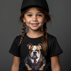 May include: A black t-shirt featuring a detailed illustration of a bulldog wearing a suit, tie, and a rose. The bulldog has brown and white fur. The shirt is worn by a person wearing a black cap.