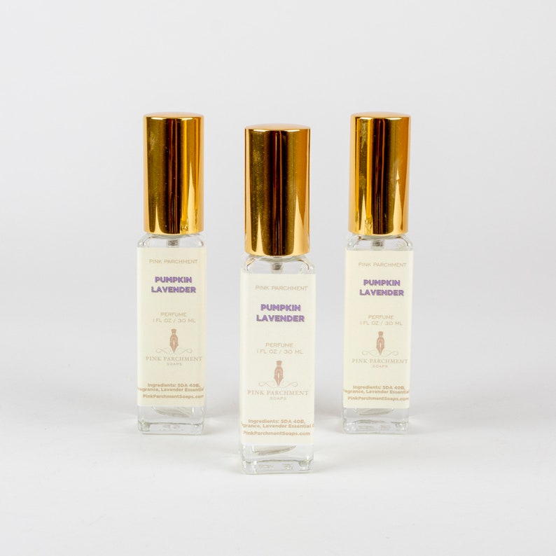 May include: Three perfume bottles with gold caps and clear glass bodies. Each bottle has a label that reads "Pumpkin Lavender" and "Perfume 1 fl oz / 30 ml". The bottles are from Pink Parchment.