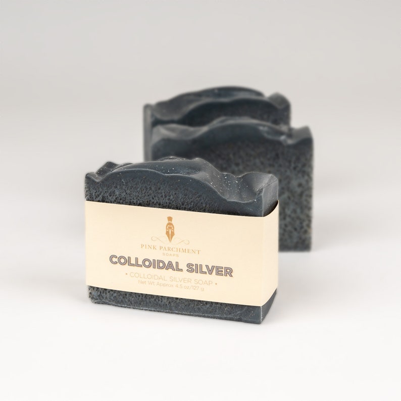May include: Three dark gray bars of soap with a textured surface. The front bar has a cream-colored label with the text "COLLOIDAL SILVER" and "COLLOIDAL SILVER SOAP". The soap weighs approximately 4.5 oz.