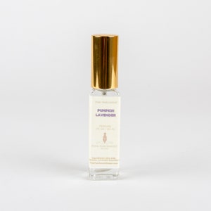 May include: A clear glass perfume bottle with a gold cap. The label reads "Pumpkin Lavender" and "Perfume 1 fl oz / 30 ml". The bottle is from Pink Parchment Soaps.