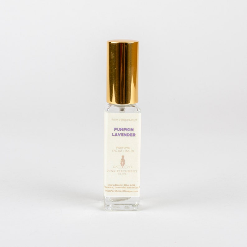 May include: A clear glass perfume bottle with a gold cap. The label reads "Pumpkin Lavender" and "Perfume 1 fl oz / 30 ml". The bottle is from Pink Parchment Soaps.