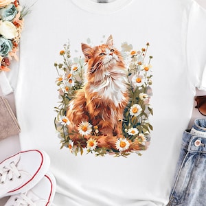 May include: White t-shirt with a graphic of a ginger cat sitting in a field of white daisies.