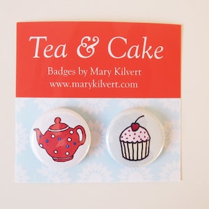 Könnte beinhalten: Zwei weiße runde Abzeichen mit roten und weißen Designs. Das linke Abzeichen zeigt eine rote Teekanne mit weißen Punkten. Das rechte Abzeichen zeigt einen weißen Cupcake mit rosa Zuckerguss und einer roten Kirsche oben drauf. Die Abzeichen befinden sich auf einem weißen Hintergrund mit einer roten Kopfzeile, auf der "Tea & Cake" und "Badges by Mary Kilvert www.marykilvert.com" steht.