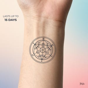 Peut inclure: Un tatouage temporaire noir présentant un motif géométrique circulaire complexe avec divers symboles alchimiques et lignes. Le texte "LASTS UP TO 15 DAYS" est imprimé en noir dans le coin supérieur gauche et un petit logo est en bas à droite.