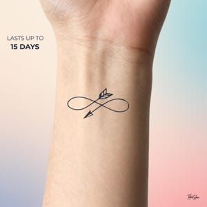 May include: A temporary tattoo featuring a dark blue infinity symbol pierced by an arrow. The tattoo is applied to the wrist. Text above the tattoo reads "LASTS UP TO 15 DAYS".