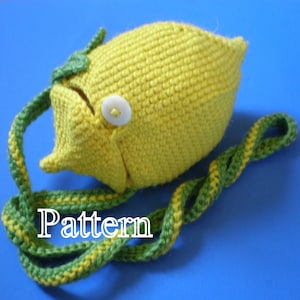 May include: A crocheted lemon-shaped purse with a green leaf detail and a white button. The purse has a long green and yellow crocheted strap.