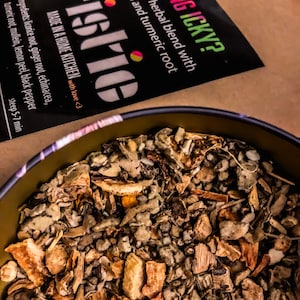 May include: Close-up of a brown and beige herbal tea blend in a metal container. The tea is labeled "Feeling Icky?" and is a spiced herbal blend with mullein and turmeric root. The label also says "Made in a home kitchen with love."