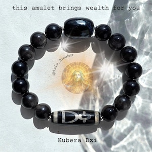 May include: A beaded bracelet featuring smooth black spherical beads, one larger oval black bead, and a cylindrical black bead with a white etched symbol. The text "this amulet brings wealth for you" and "Kubera Dzi" is visible on the image.