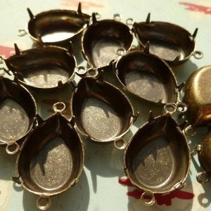 May include: A collection of 10 antique gold-toned metal settings for cabochons. The settings are shaped like teardrops and have a smooth, polished finish.