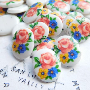 May include: Assortment of white oval buttons with floral designs. The buttons feature pink roses, blue and yellow flowers, and green leaves.