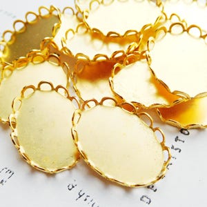 May include: A group of gold-colored metal oval-shaped embellishments with a decorative scalloped edge.