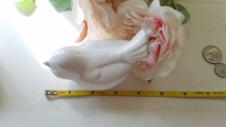May include: White ceramic bird figurine with a detailed tail and a smooth, glossy finish. The bird is approximately 5 inches long.