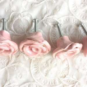 May include: Set of four pink ceramic rose-shaped drawer pulls with silver screws.