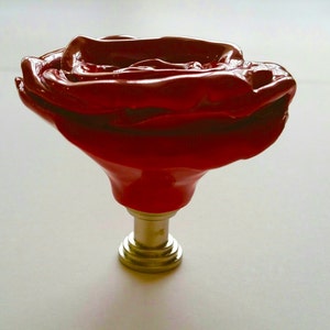 以下が含まれることがあります： 金色の金属製のベースが付いた、赤いバラの形をしたセラミック製のキャビネットノブです。