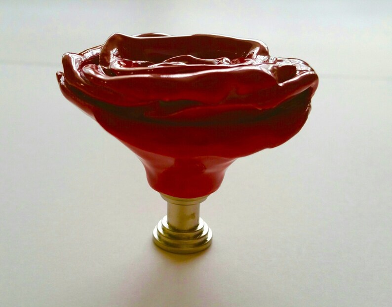 以下が含まれることがあります： 金色の金属製のベースが付いた、赤いバラの形をしたセラミック製のキャビネットノブです。