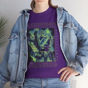 May include: A purple t-shirt with a neon green and blue graphic of the Transformers character Soundwave. The design includes the text "SOUNDWAVE" and "DECEPTICONS". The shirt is worn with a denim jacket and blue jeans.