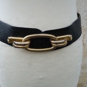 May include: A black leather belt with a large gold-toned buckle featuring a linked chain design.