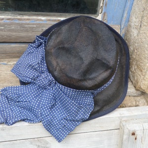May include: A black straw hat with a blue and white polka dot ribbon tied around it.