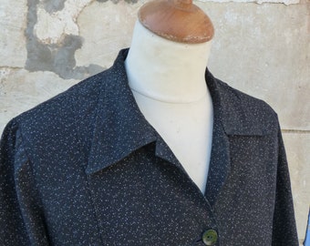 May include: A black long-sleeved shirt with a white polka dot pattern and a collared neckline. The shirt has a button-up front and two buttons visible.