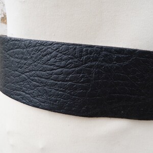 May include: A wide black leather belt with a textured surface.