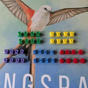 May include: A set of colorful birdhouse game pieces. There are 12 green, 12 yellow, 12 purple, 12 blue, and 12 red birdhouses. The birdhouses are arranged in rows of six. The background is a blue and green watercolor painting of a bird in flight.