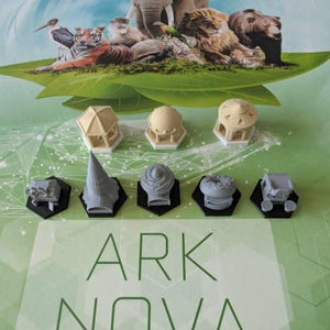 May include: A set of eight grey and beige plastic game pieces for the board game Ark Nova. The pieces are on a green and white background with the words "Ark Nova" printed on the bottom.