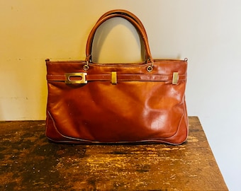 May include: A brown leather tote bag with gold hardware and a top handle.
